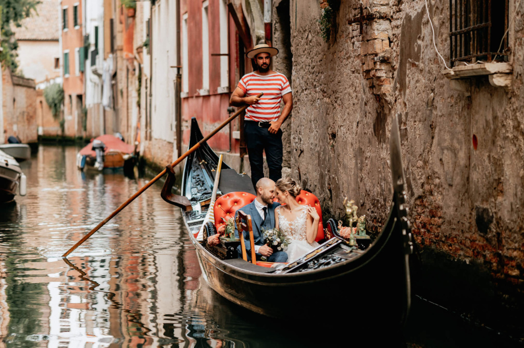 Brautpaar in einer Gondel in Venedig, umgeben von malerischen Kanälen und historischen Gebäuden.