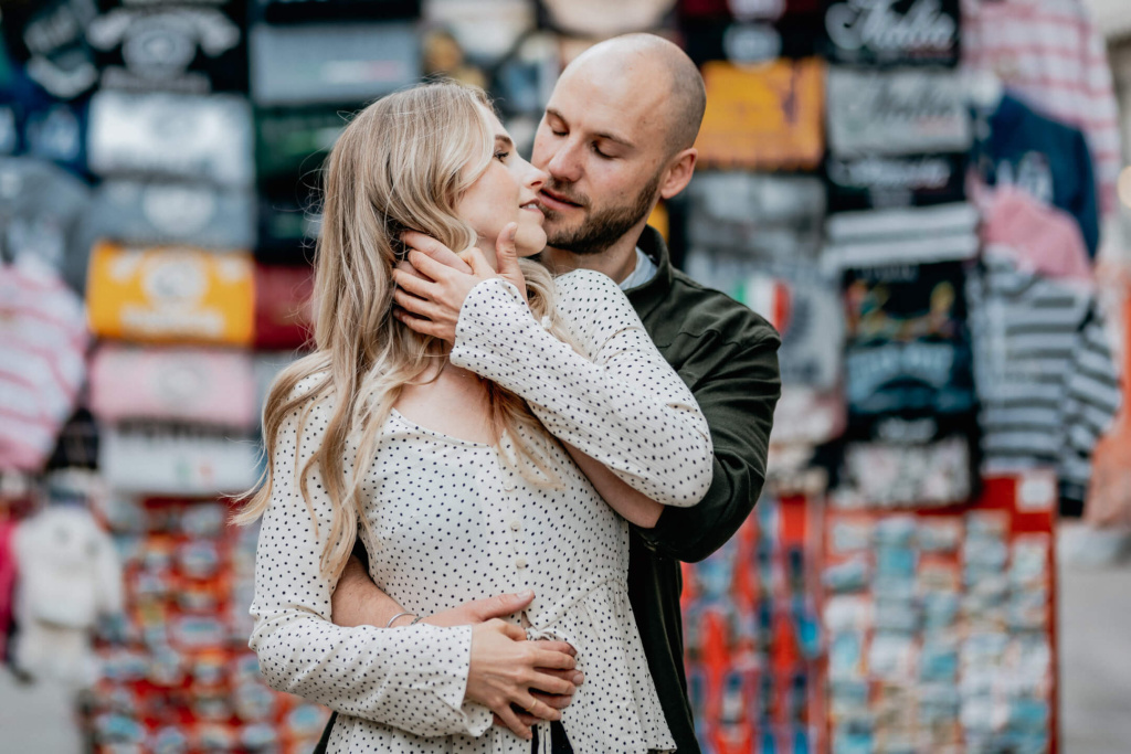 Paar in inniger Umarmung vor buntem Stoffhintergrund, emotionale Hochzeitsfotografie.
